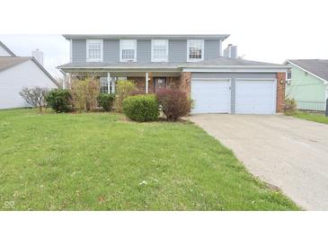 Charming two-story home with a well-manicured lawn and an attached two-car garage at 7421 Rogers Dr, Indianapolis, IN 46214
