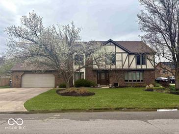 Charming two-story home with brick and Tudor accents, a well-manicured lawn, and an attached two-car garage at 8212 N Sierra Dr, Muncie, IN 47303