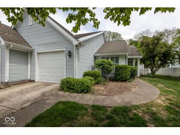 Charming home featuring light blue siding, attached garage, and meticulously landscaped front yard at 9029 Crook N Dr, Indianapolis, IN 46256