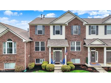 Charming two-story brick townhome featuring neat landscaping, gray shutters, and a welcoming front entrance at 12658 Watford Way, Fishers, IN 46037