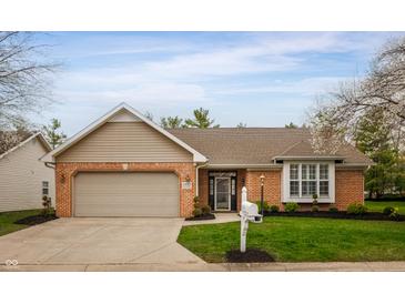 Charming brick home featuring an attached garage, well-manicured lawn, and blossoming trees at 2813 W Long Meadow Ln, Muncie, IN 47304