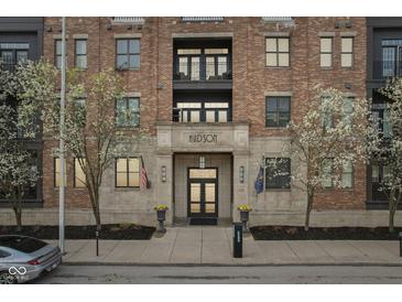 Beautiful brick building with stone accents, flags, flowering trees, and black framed windows at 355 E Ohio St # 309, Indianapolis, IN 46204