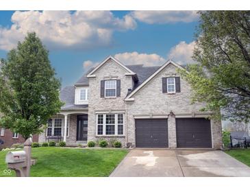 Beautiful two-story brick home featuring a two-car garage, well-manicured lawn, and mature trees at 10365 Aurora Ct, Fishers, IN 46038