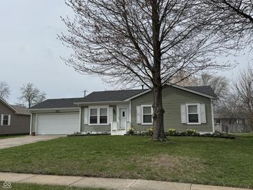 Charming single story home with green lawn and a two-car garage, enhanced by a mature shade tree at 1424 Ashley Dr, Lebanon, IN 46052