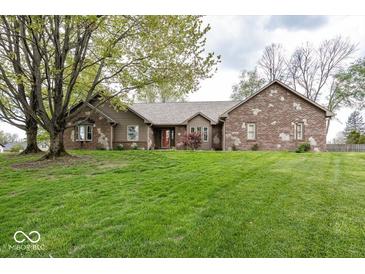 Charming brick home features a lush green lawn, mature trees, and a welcoming red front door at 1509 Copperwood Pl, Carmel, IN 46033
