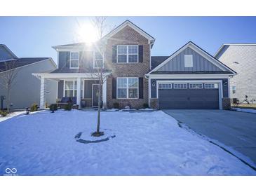 Two-story home with brick and siding, a two-car garage, and a small tree in the snowy front yard at 15365 Todd S Ln, Fishers, IN 46037