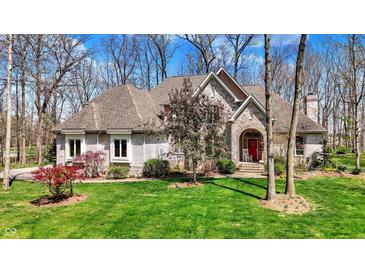 Charming exterior featuring manicured lawn, stone facade, and arched entryway with red door at 23219 Marin Dr, Cicero, IN 46034