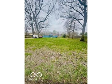 View of the home with a large front yard featuring a mature tree line at 3126 Newhart St, Indianapolis, IN 46217