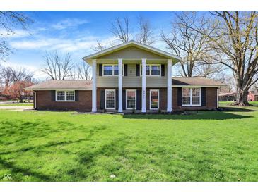 Charming two-story home with a brick facade, lush green lawn, and beautiful trees on a sunny day at 5311 Larita Ln, Anderson, IN 46017