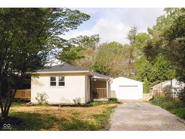 Charming home featuring a detached garage, wood deck, and gravel driveway lined with trees at 5820 Bonnie Brae St, Indianapolis, IN 46228