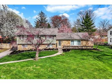 Beautifully landscaped home with a stone and siding exterior and a lush green lawn at 6377 Green Leaves Rd, Indianapolis, IN 46220