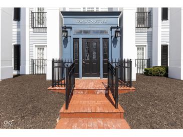 Inviting building entrance features red brick steps, a black door, and blue accents at 12926 University Cres # 2C, Carmel, IN 46032