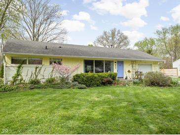 Charming single-story home featuring a blue front door, well-maintained lawn, and a lush landscaped garden at 2816 Canterbury Ln, Indianapolis, IN 46220