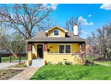Charming yellow home with a dormer window, quaint front porch and well-maintained lawn at 3484 Birchwood Ave, Indianapolis, IN 46205