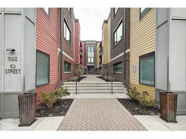 Exterior view of colorful townhomes with brick and siding, plus a brick walkway and landscaping at 622 E 10Th St # 303, Indianapolis, IN 46202