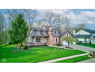 Charming two-story home with brick facade, covered porch, manicured lawn, and attached two-car garage at 8695 Shoe Overlook Dr, Fishers, IN 46038