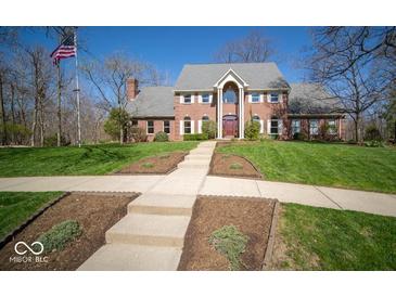 Beautiful red brick home with manicured lawn and landscaped beds and an American flag at 6013 Yellow Birch Ct, Avon, IN 46123