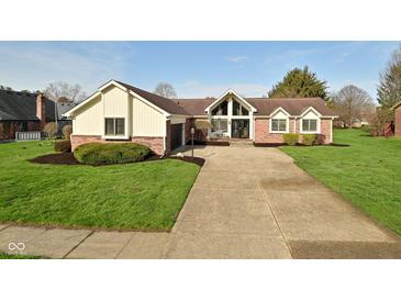 Charming brick home featuring a well-manicured front yard, a long driveway, and an attached garage at 6276 Quail Rdg W Dr, Plainfield, IN 46168