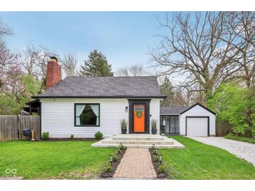 Charming home features a bright orange door, updated landscaping, and a brick chimney at 6481 Michigan Rd, Indianapolis, IN 46268