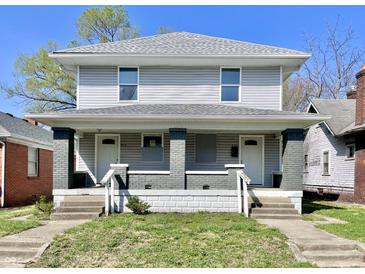 Two-story duplex with gray siding, covered front porches, and steps leading to separate entrances at 918 N Dearborn St, Indianapolis, IN 46201