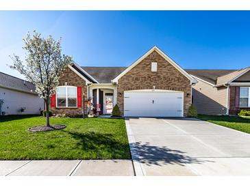 Charming brick home featuring a well-manicured lawn, blossoming tree, and attached two-car garage, all under a clear blue sky at 1371 Blackthorne N Trl, Plainfield, IN 46168