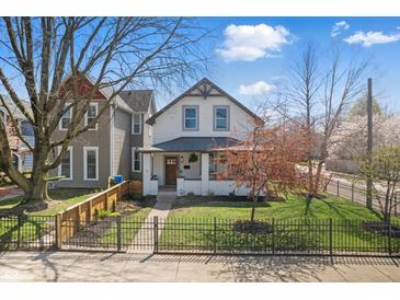 Charming two-story home featuring a landscaped front yard with mature trees and an inviting front porch at 1403 Fletcher Ave, Indianapolis, IN 46203