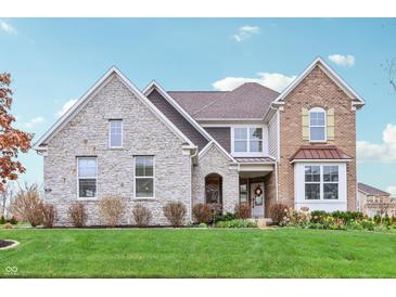 Beautiful two-story home with stone and brick facade, lush lawn, and well-maintained landscaping at 3665 Conifer Dr, Zionsville, IN 46077