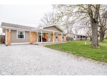 Charming single-story home featuring a covered front porch, brick accents, and a gravel driveway at 504 W Dwain, Shelbyville, IN 46176