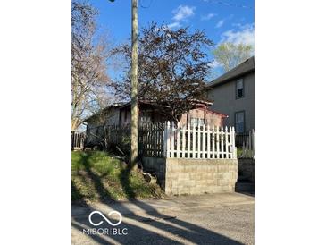Quaint home featuring a white picket fence and partial brick foundation, nestled on a small lot at 549 N Traub Ave, Indianapolis, IN 46222