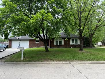 Charming brick home with a well-maintained lawn and mature trees offering shade and curb appeal at 605 Queenswood Dr, Indianapolis, IN 46217