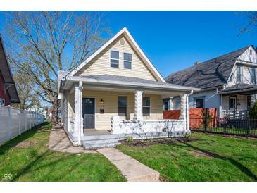 Charming two-story home featuring a gabled roof, inviting front porch and well-manicured lawn under a clear blue sky at 106 N Linwood Ave, Indianapolis, IN 46201