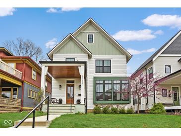 Charming two-story home with a covered porch, manicured lawn, and beautiful green and white color scheme at 2134 N New Jersey St, Indianapolis, IN 46202