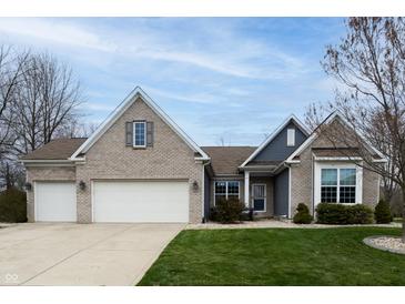 Charming brick home featuring a two-car garage, manicured lawn, and classic architectural details under a beautiful sky at 2890 Trillium Way, Columbus, IN 47201