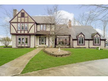 Charming Tudor-style home with a well-manicured lawn and decorative fountain at 3892 Arrowhead Ct, Greenfield, IN 46140