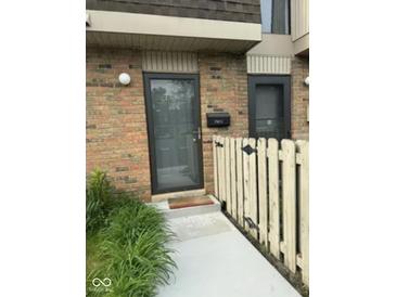 Brick townhouse entrance featuring a gray door, mailbox, and light fixture at 7411 Country Brook Dr, Indianapolis, IN 46260