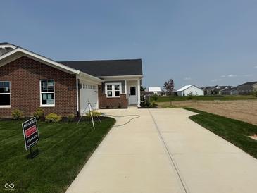 Charming brick home featuring a long driveway, well-manicured lawn, and attached two-car garage at 7421 Broadview Ln, McCordsville, IN 46055