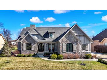 Charming stone and siding home with a well-manicured lawn and a lovely walkway leading to the front door at 3582 Pete Dye Blvd, Carmel, IN 46033