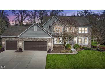 Charming two-story home featuring a brick facade, attached garage, and manicured lawn at 9789 Logan Ln, Fishers, IN 46037