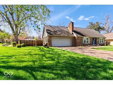 Charming brick home with attached garage, complemented by a lush green lawn and mature trees at 10533 Williamsburg Dr, Newburgh, IN 47630