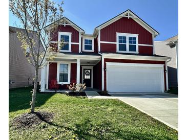 Charming two-story home featuring vibrant red siding, white trim, a well-manicured lawn, and an attached two-car garage at 1380 Delacorte Cir, Shelbyville, IN 46176