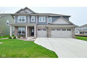 Charming two-story home boasts a three-car garage and well-manicured lawn at 5181 Golden Grove Dr, McCordsville, IN 46055