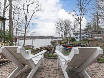 Inviting brick patio featuring two white Adirondack chairs overlooking a serene lake and private boat dock at 6599 Meadowlark Dr, Nineveh, IN 46164
