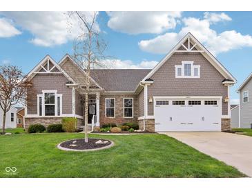 Charming home featuring stone accents, a two-car garage, and a well-manicured lawn at 13494 Moorcroft Dr, Fishers, IN 46037