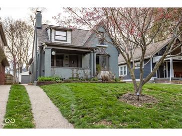 Charming two-story home with a lush front yard and inviting curb appeal showcasing it's quaint architectural details at 5654 Broadway St, Indianapolis, IN 46220