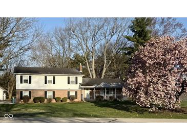 Charming two-story home with brick and vinyl siding, mature landscaping, and flowering tree at 6436 Lakeland Blvd, Indianapolis, IN 46234