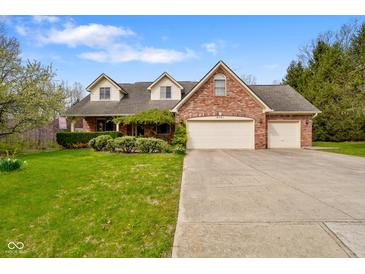Inviting two-story brick home with a three-car garage and well-manicured lawn and landscaping at 6761 E Woodland Ct, Mooresville, IN 46158