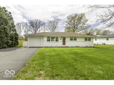 Charming single-story home with a well-manicured lawn and a paved driveway leading to an attached garage at 7144 Lockwood Ln, Indianapolis, IN 46217