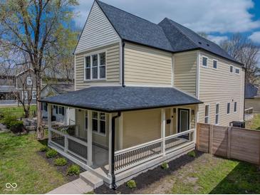 Inviting two-story home with a covered front porch and manicured lawn at 2209 Carrollton Ave, Indianapolis, IN 46205