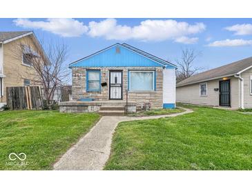 Charming single-story home with stone and siding, complemented by a well-manicured lawn and blue accents at 3924 E 30Th St, Indianapolis, IN 46218