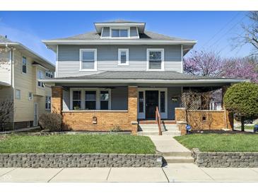 Charming two-story home with gray siding, brick accents, and a well-manicured front lawn under a clear blue sky at 3970 Broadway St, Indianapolis, IN 46205